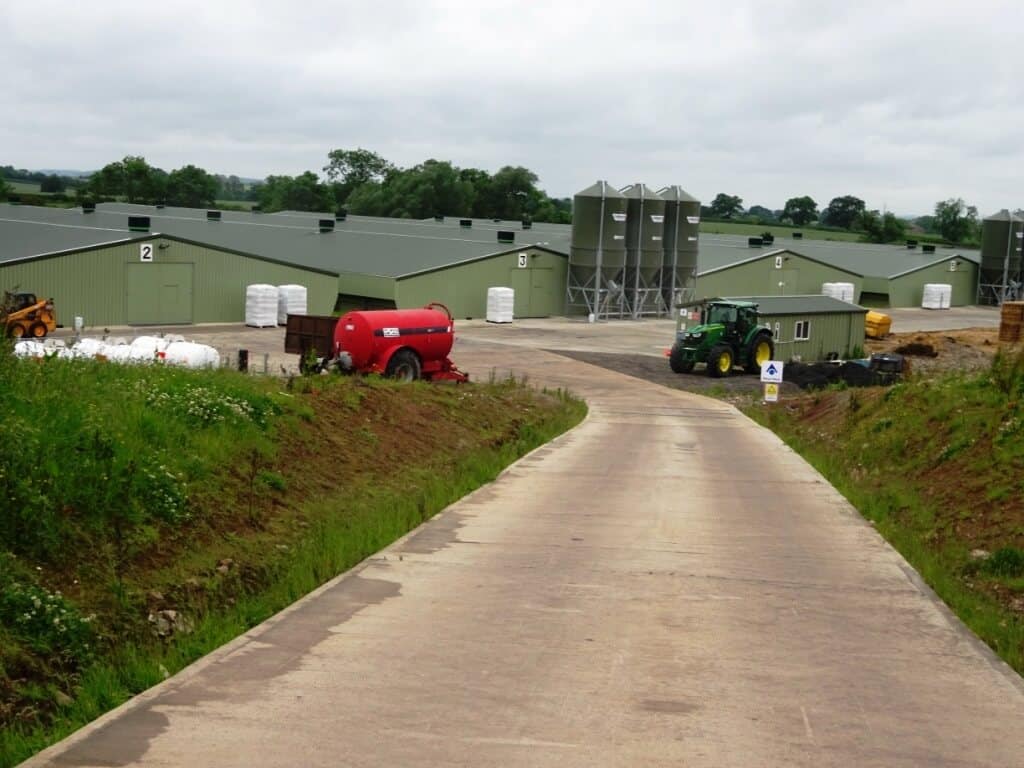 Farm road with buildings and farm vehicles in background
